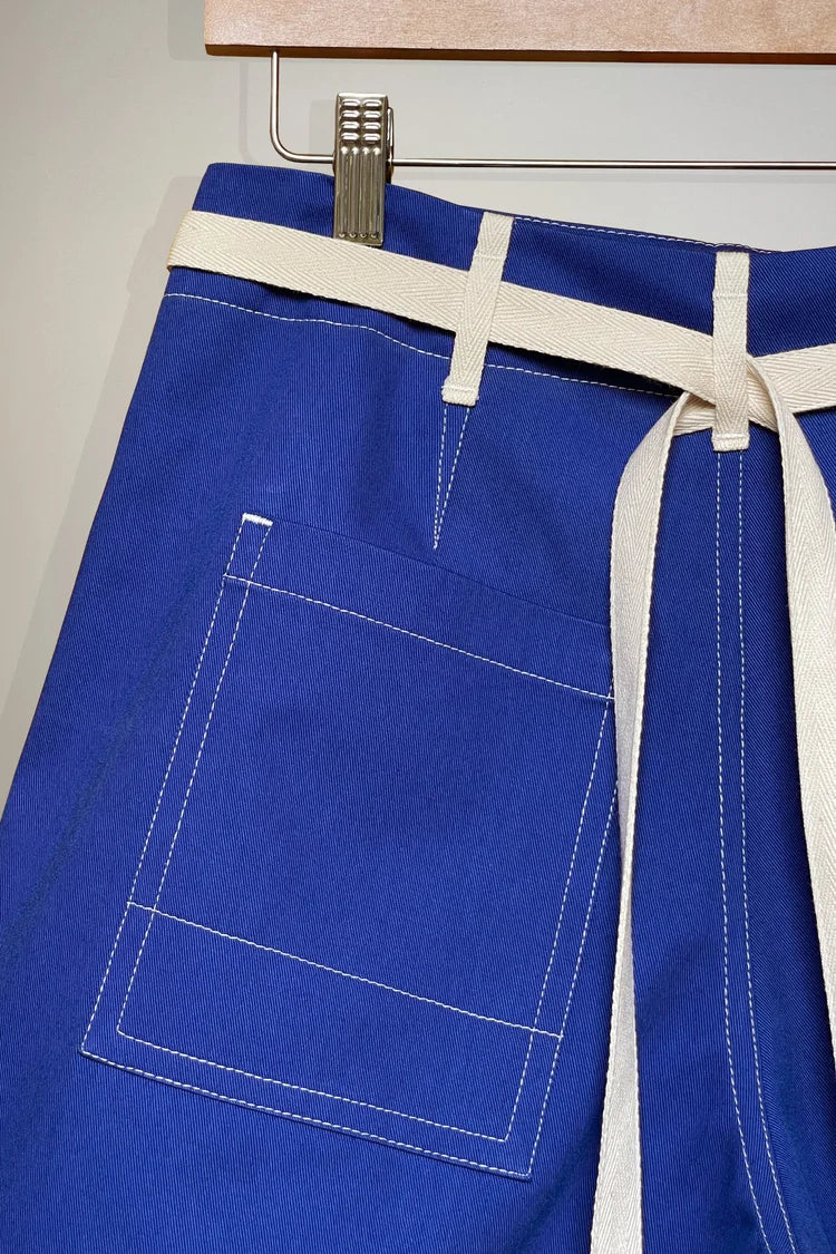 Blue trousers with a white belt hanging on a hook