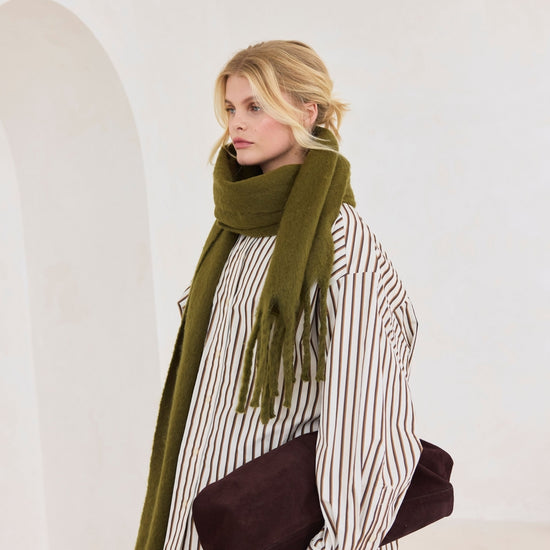 Woman wearing a green scarf and striped shirt against a white background