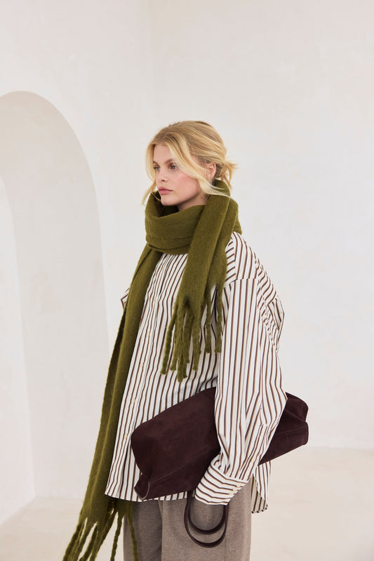 Woman wearing a green scarf and striped shirt against a white background
