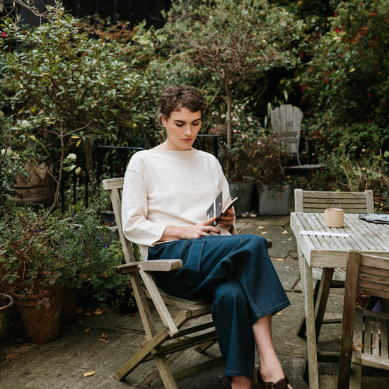 Woman sitting outdoors in a garden, using a tablet.