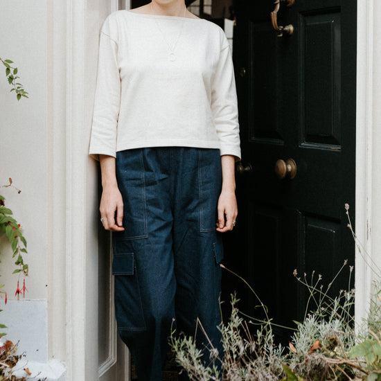 Person standing in a doorway with decorative white archway and brick wall.