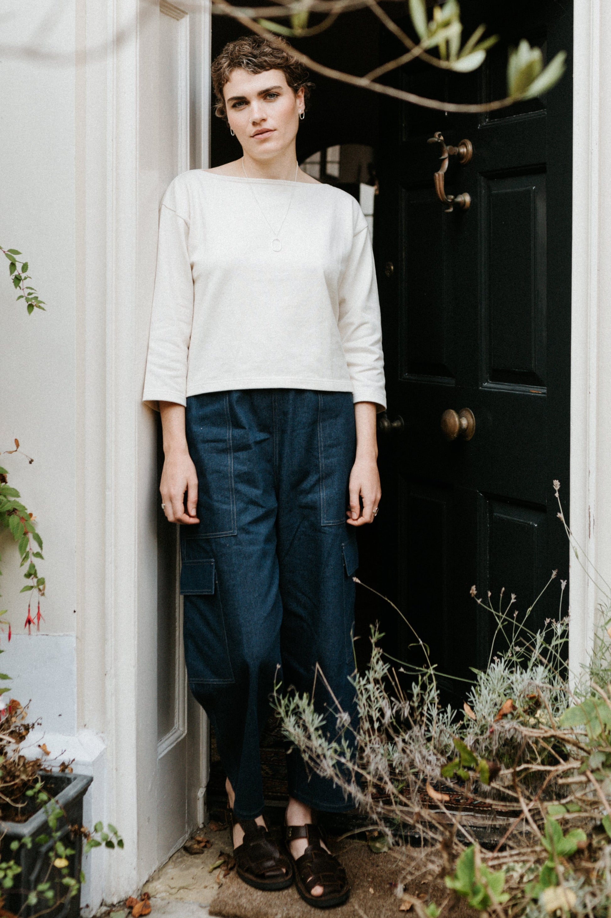 Person standing in a doorway with decorative white archway and brick wall.