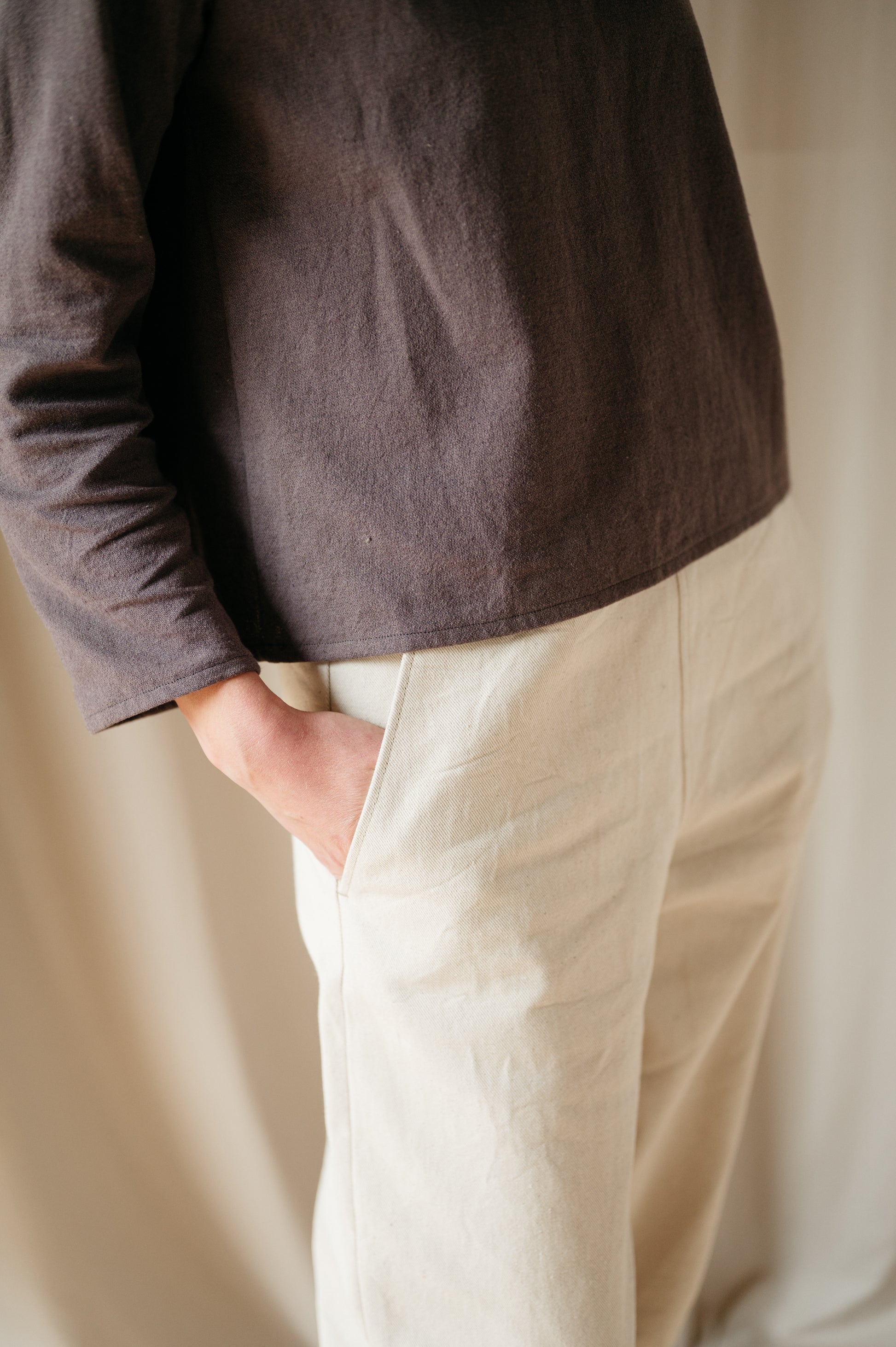 Model wearing barrel leg denim trousers, side view