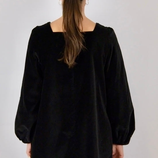 Black mini dress worn by a person with a plain background