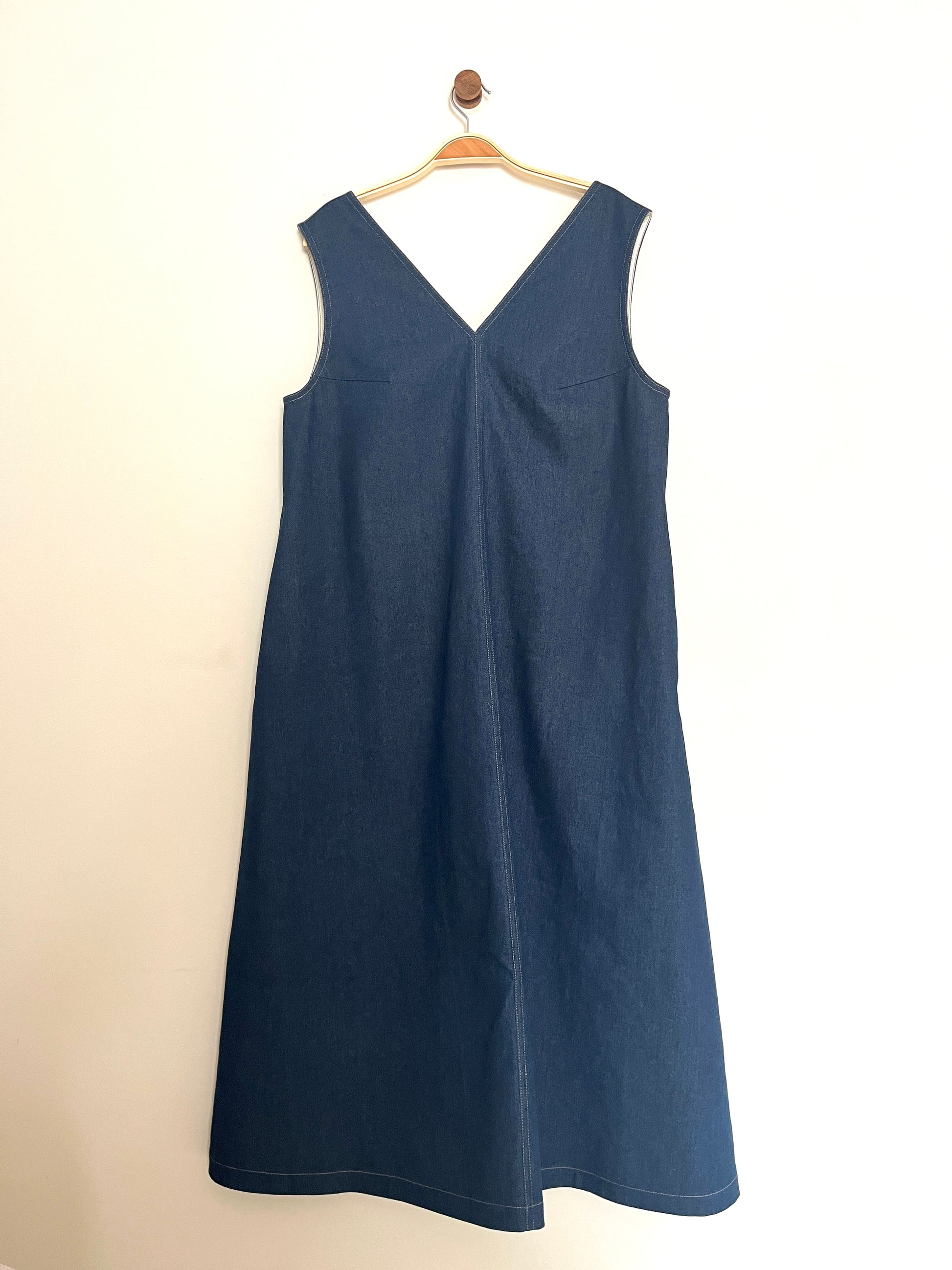 Indigo denim aline sleeveless long dress with a v-neck and centre seam on a cream background