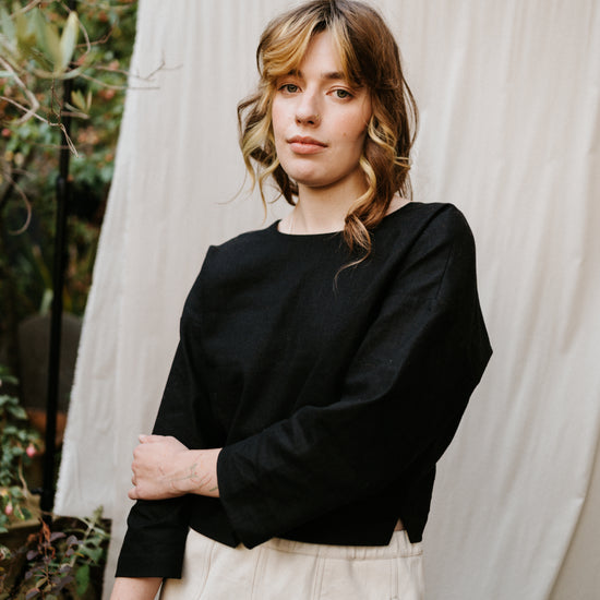 woman wearing black reversible top in ramie linen standing in a garden setting