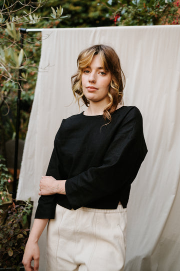 woman wearing black reversible top in ramie linen standing in a garden setting