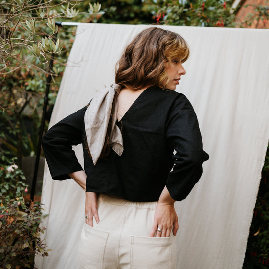 woman showing low back of black top standing in garden setting