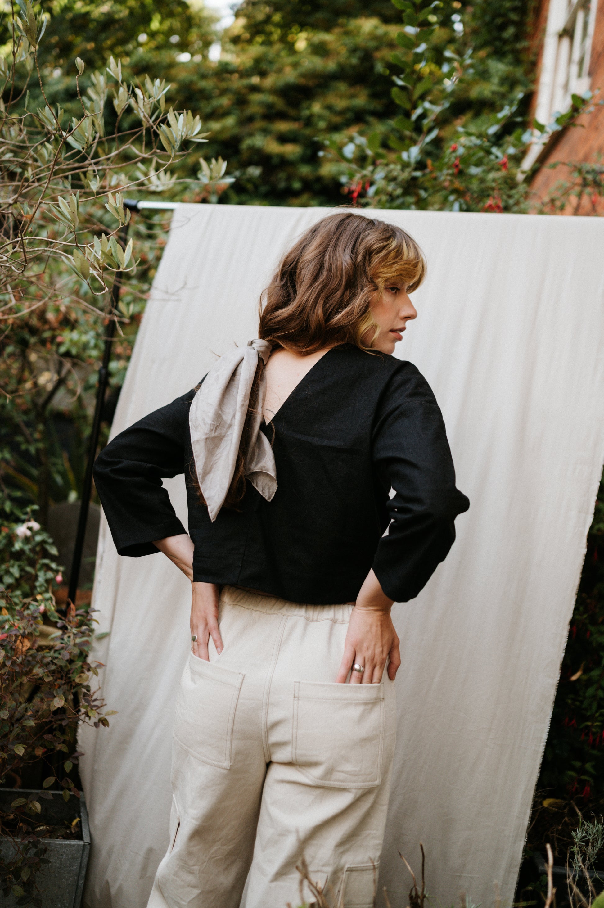 woman showing low back of black top standing in garden setting