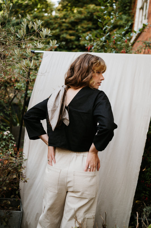 woman showing low back of black top standing in garden setting