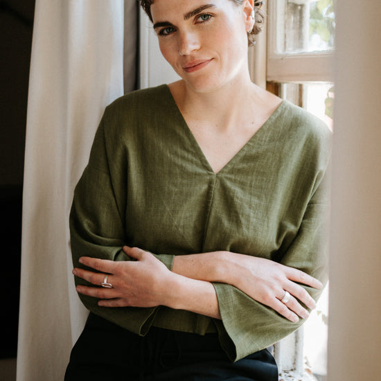 woman sitting on windowsill wearing atwin the label reversible top in khaki ramie linen