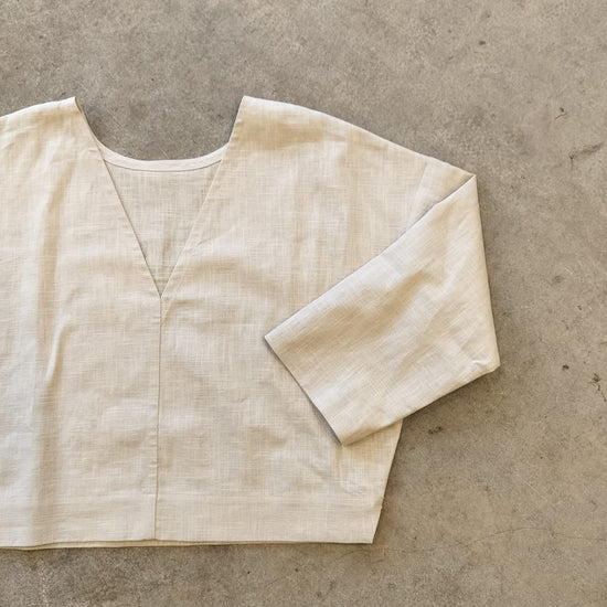 Beige reversible top on a textured gray surface