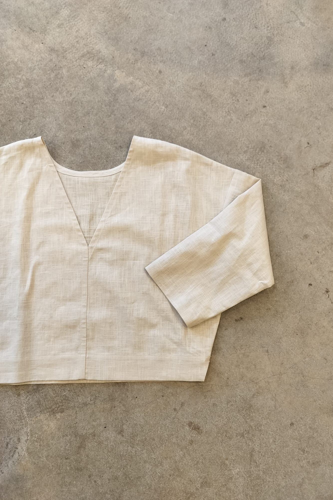 Beige reversible top on a textured gray surface