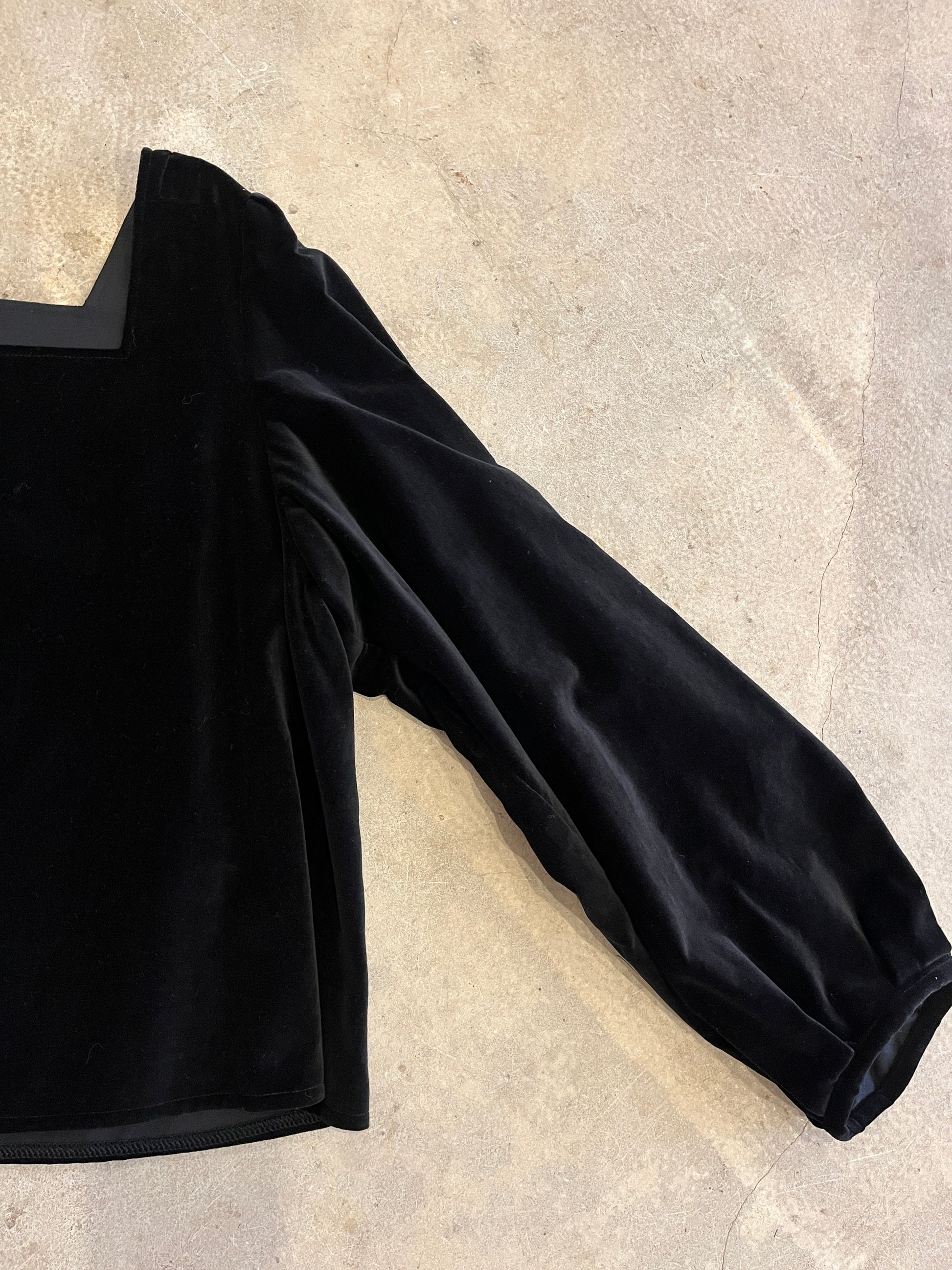 Black long-sleeve top on a light gray surface