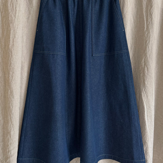Blue denim skirt on a hanger against a beige fabric background