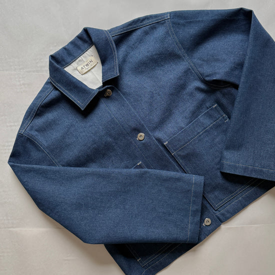 Blue denim workwear jacket with collar on a light gray background