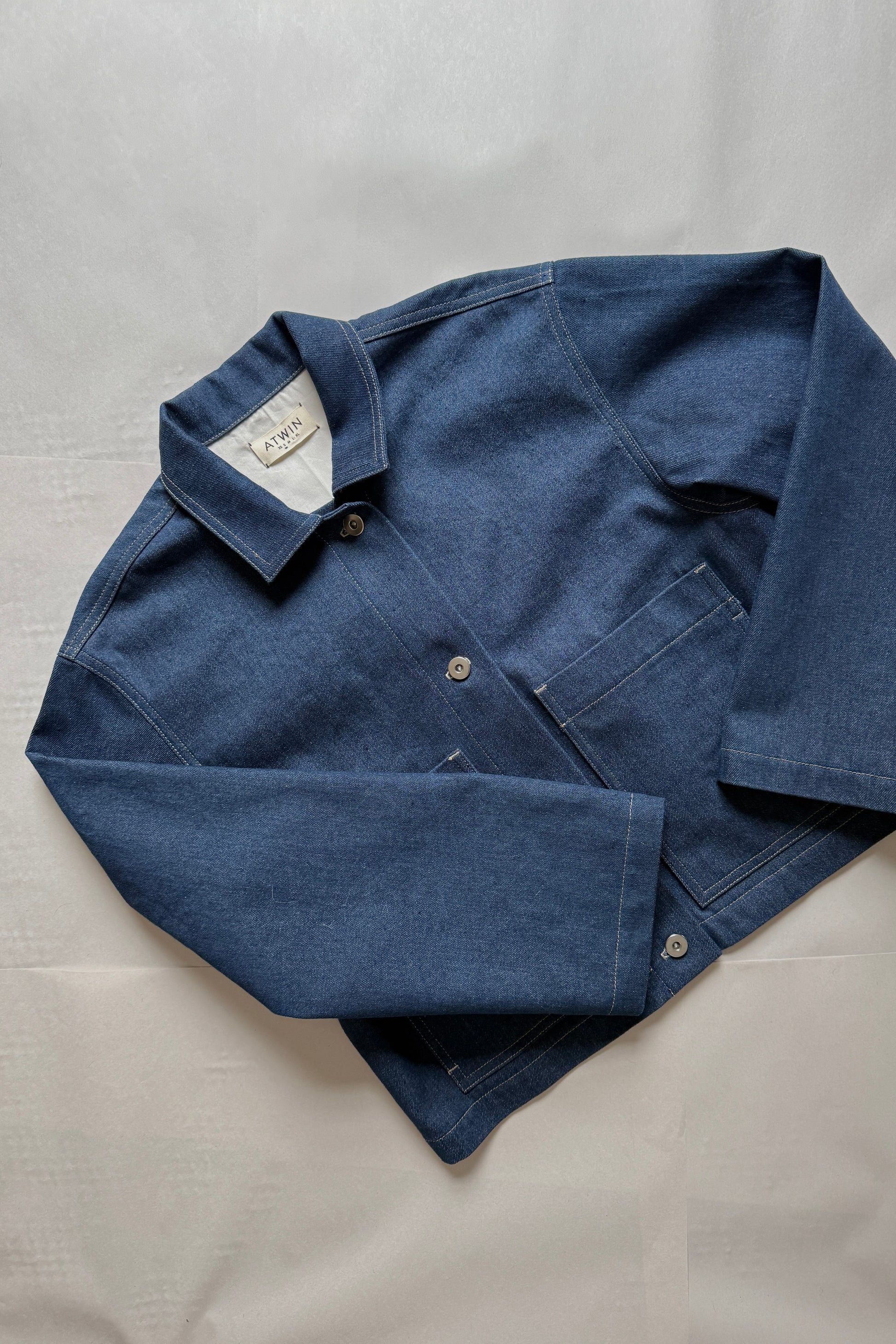 Blue denim workwear jacket with collar on a light gray background