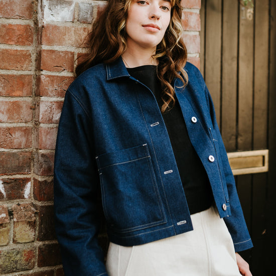 Person wearing a blue denim jacket against a brick wall