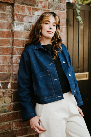 Person wearing a blue denim jacket against a brick wall