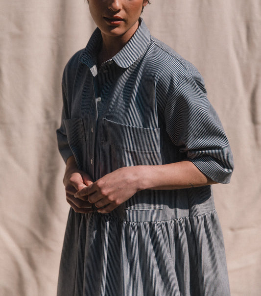 Person wearing a blue striped dress against a beige background