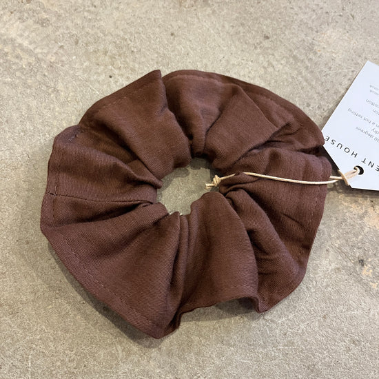 Brown scrunchie on a textured surface with a tag in the background