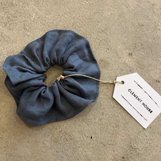 Blue scrunchie with a tag on a beige surface