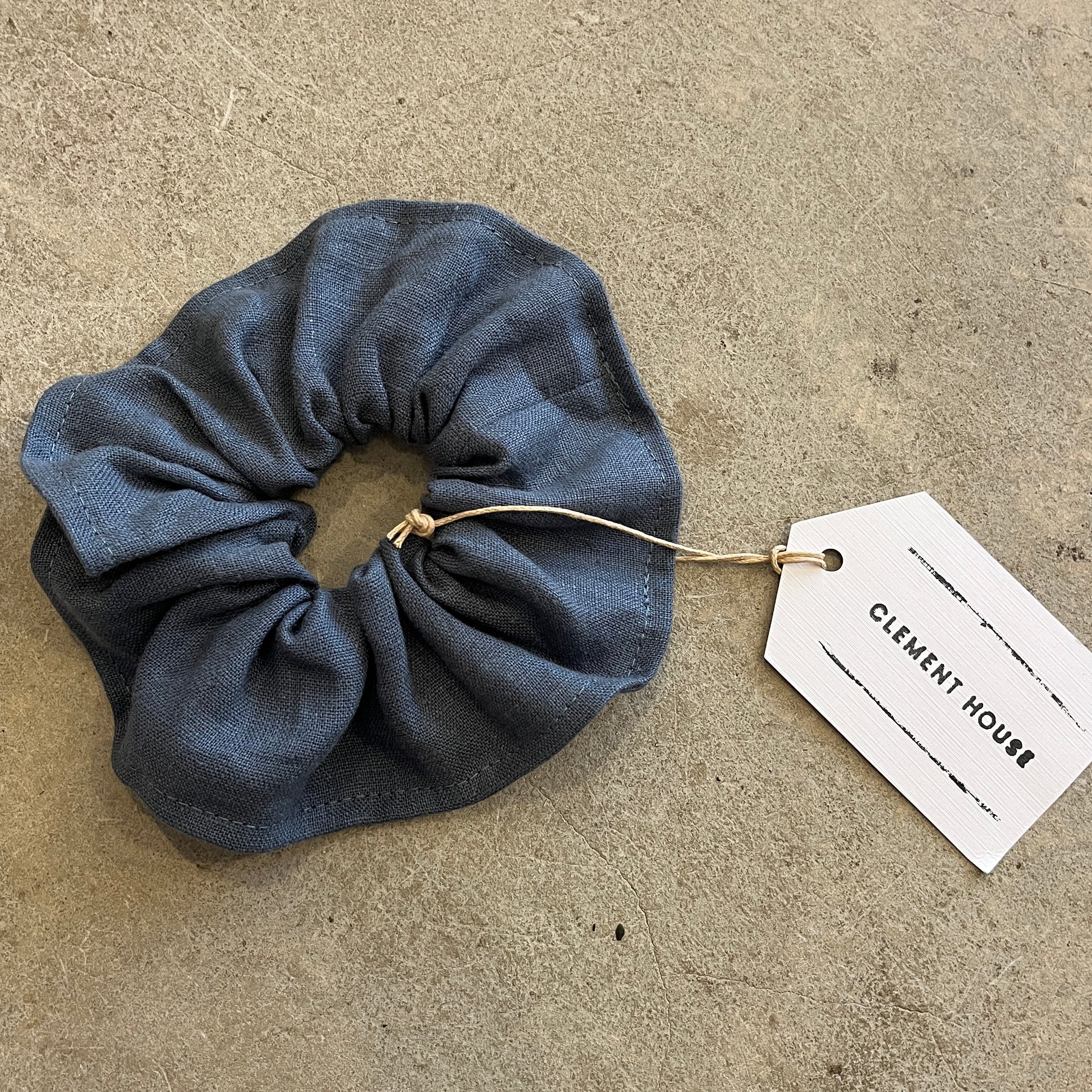 Blue scrunchie with a tag on a beige surface