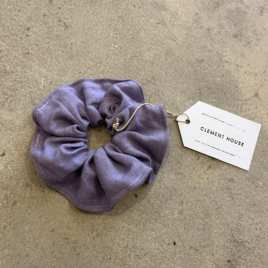 Purple scrunchie with a tag on a beige surface