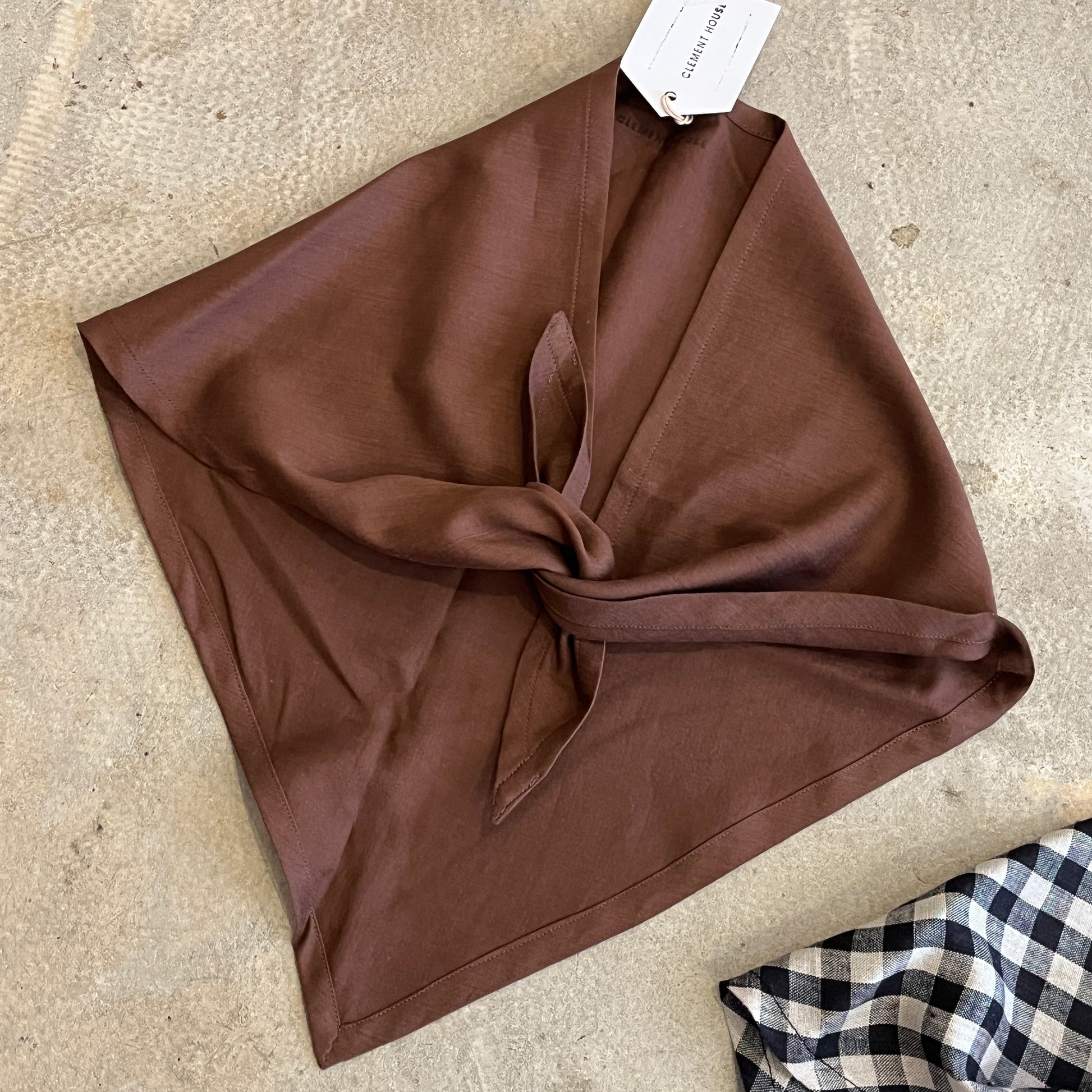 Brown cotton neck tie scarf with a tag on a beige surface