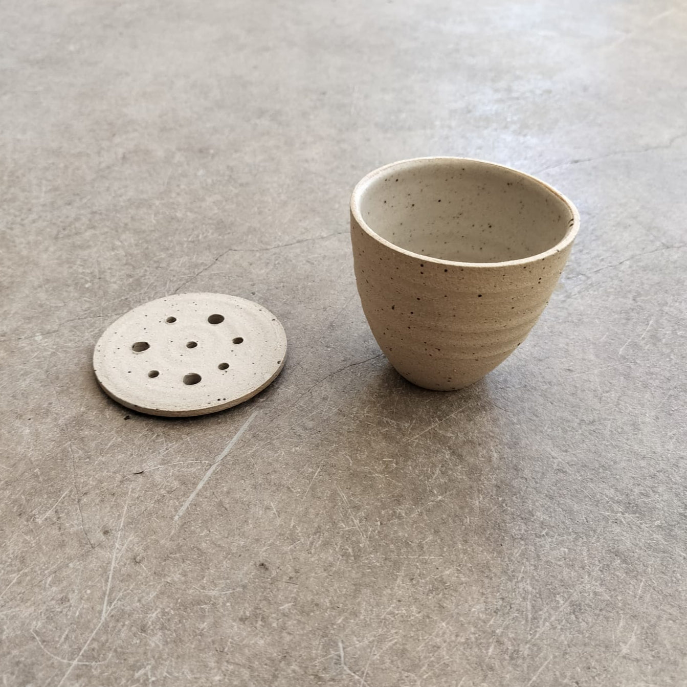 Ceramic cup and round disc on a concrete floor