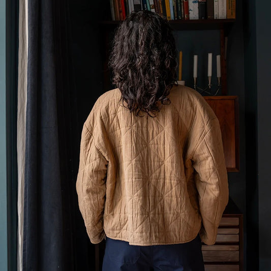 women wearing a padded jacket by elwin facing the wall