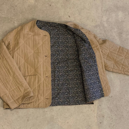 A brown, boxy fit jacket with a mandarin collar, quilted texture, and lined with a vintage dead stock Liberty Tana Lawn fabric.