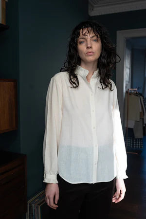 women wearing a  beige, frill-shirt with a relaxed fit.