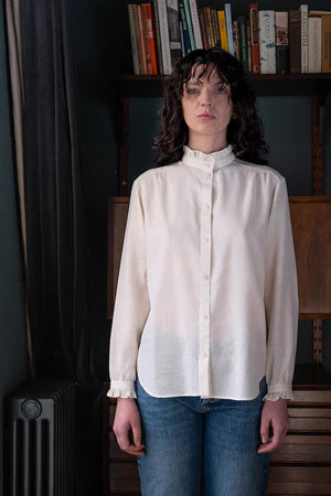 women wearing a  beige, frill-shirt with a relaxed fit.