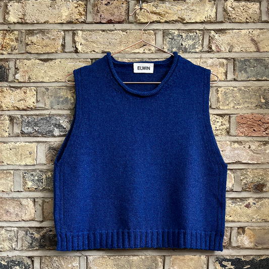 a navy knitted vest hanging on a brick wall