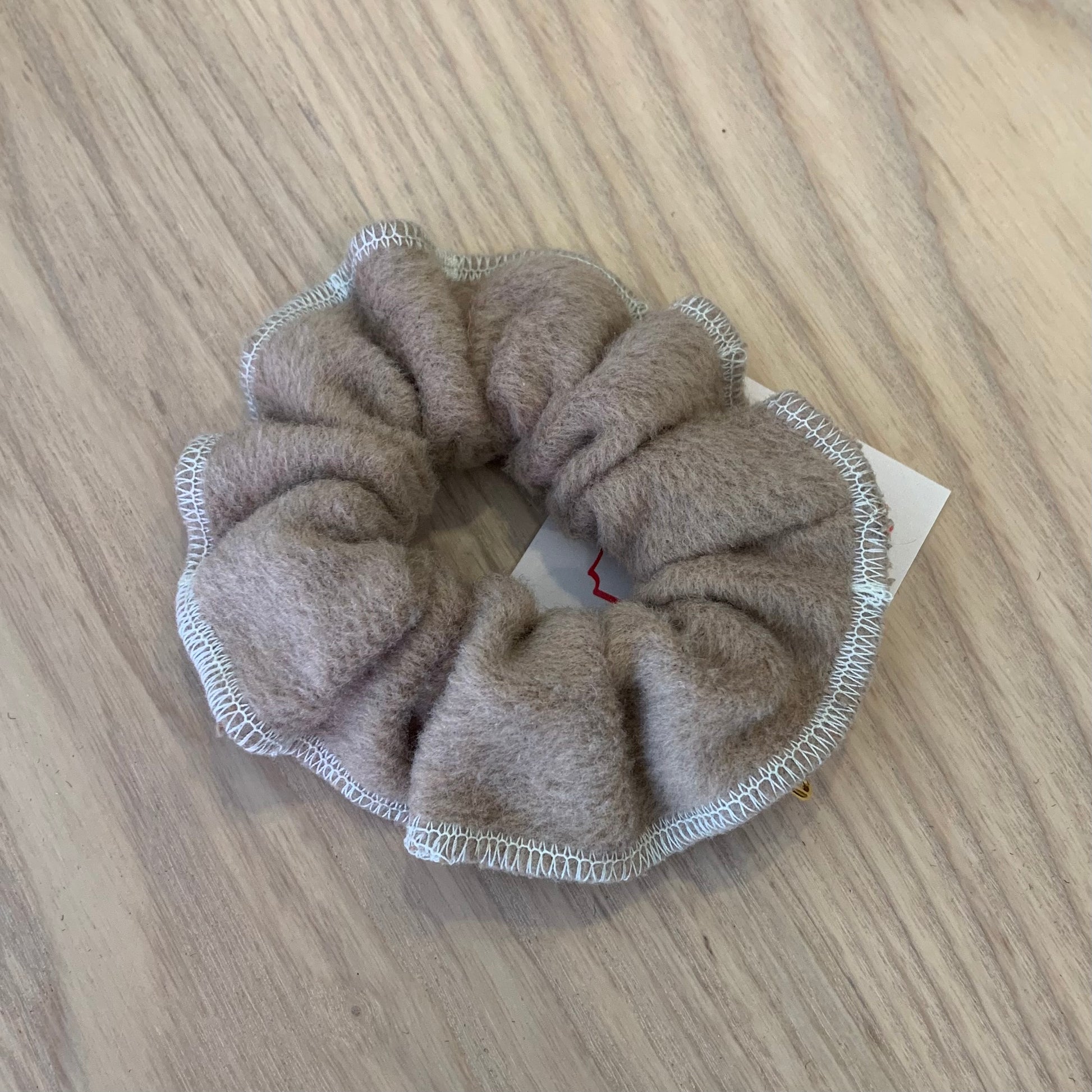 a beige wool scrunchy on a wooden background