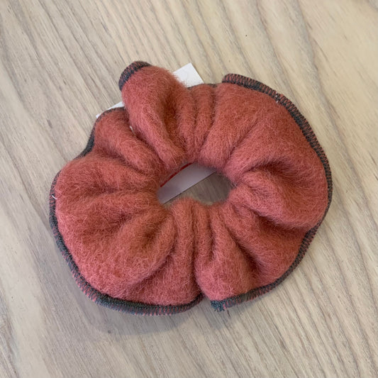 A red wool scrunchie on a wooden background