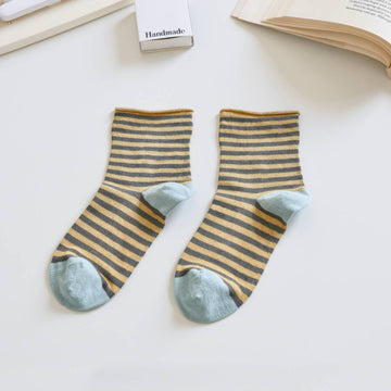 Pair of striped socks with blue toes on a light surface