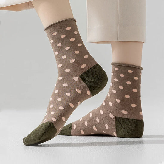 A pair of brown socks with pink dot pattern and green toe and heel, worn on a person's feet.