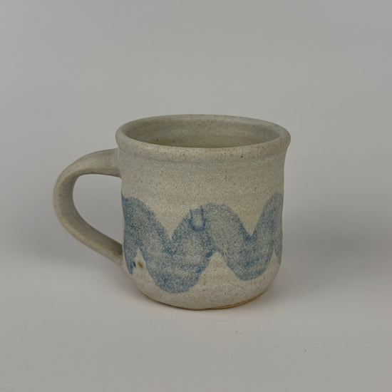 Gray ceramic mug with blue wave design on a gray background