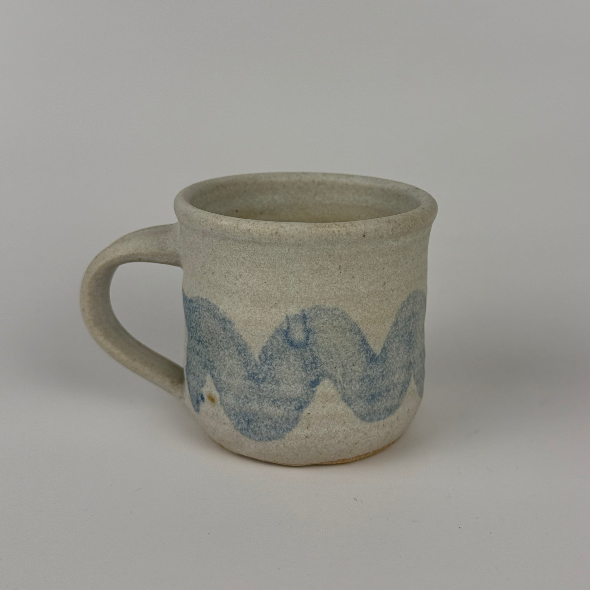 Gray ceramic mug with blue wave design on a gray background