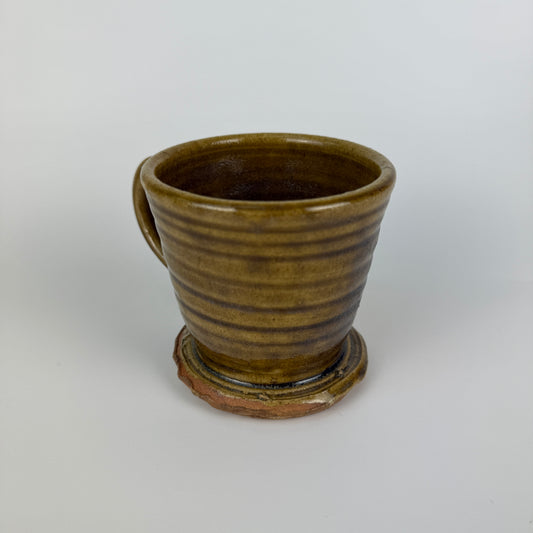 Brown ceramic cup with handle on a white background