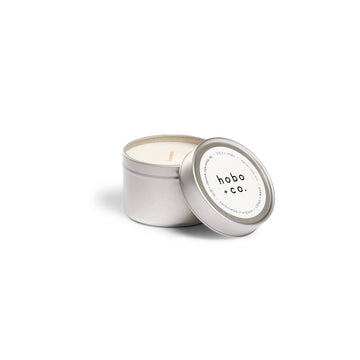 Candle in a metallic tin with 'hobo + co.' label on a white background