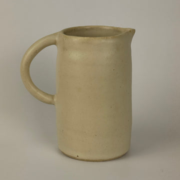 Beige ceramic pitcher on a plain background