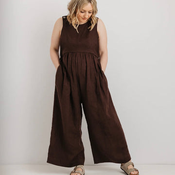 Woman wearing a brown jumpsuit against a plain background