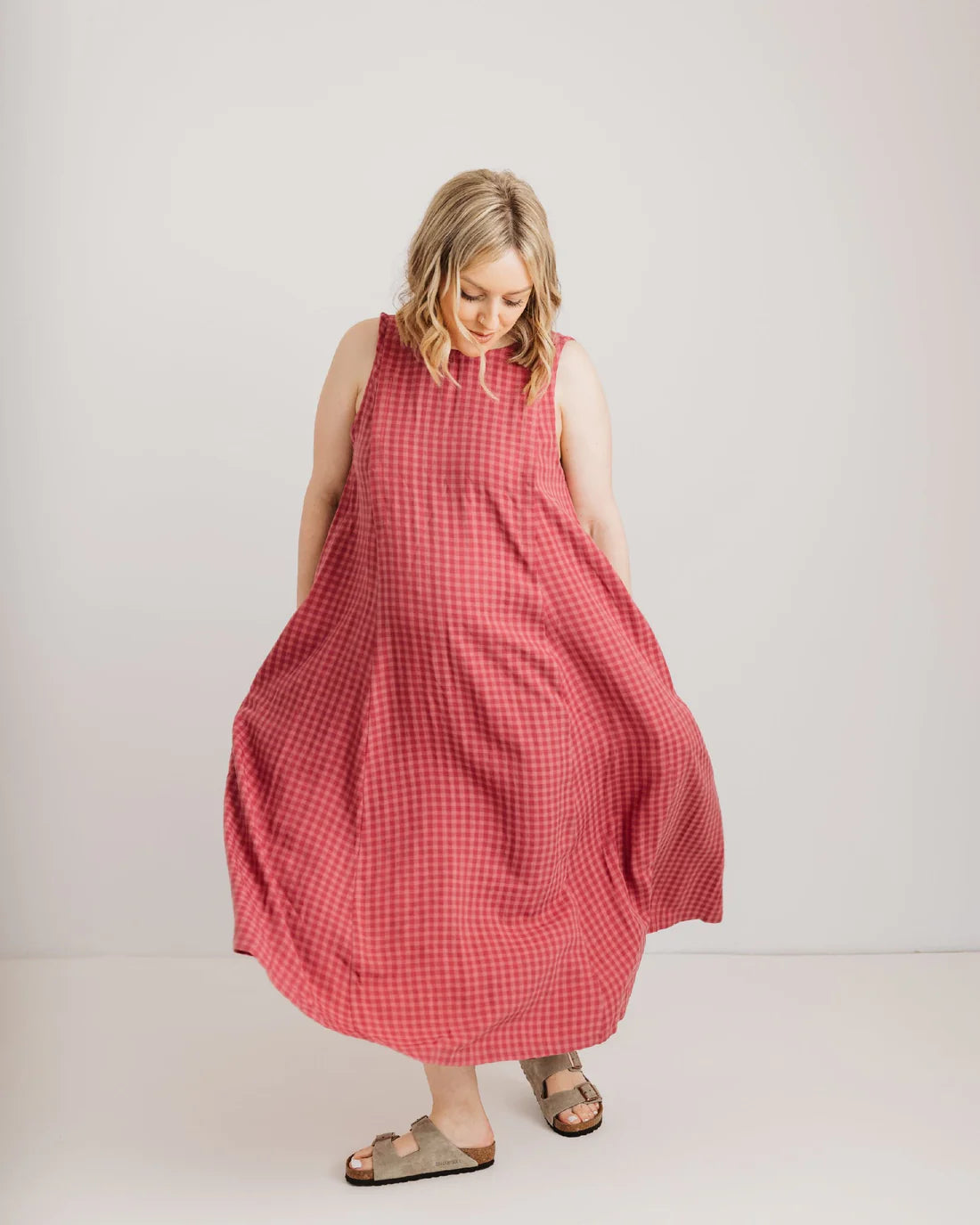 Woman wearing a pink checkered dress against a white background