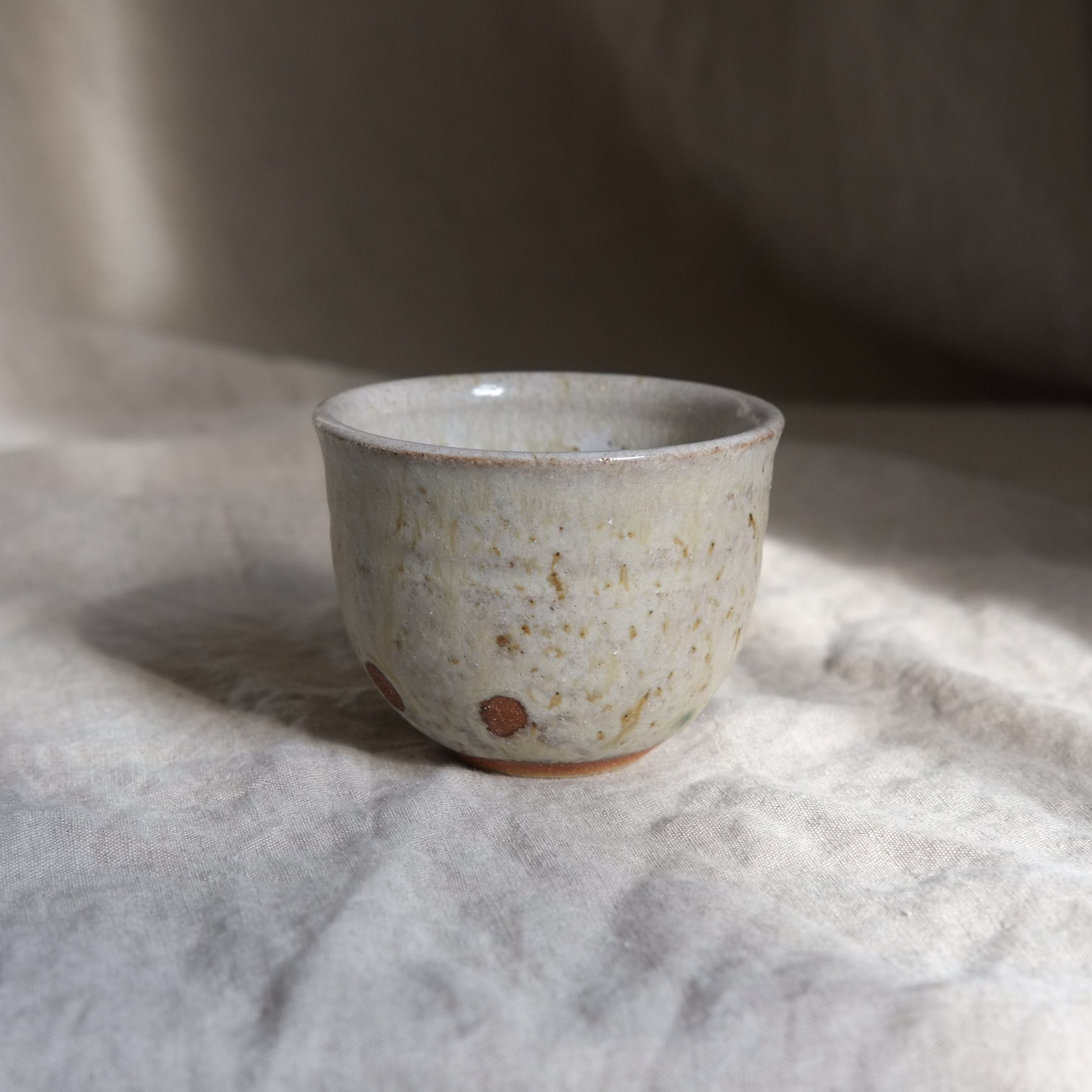 Ceramic cup with textured surface on a light fabric background