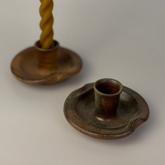 Two rustic candle holders on a plain background
