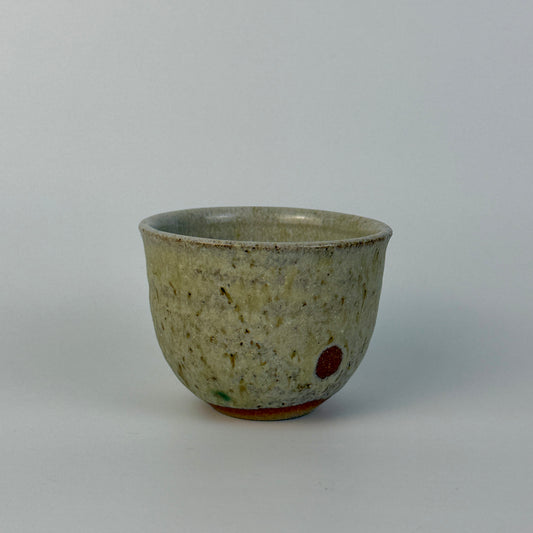 Ceramic cup with speckled glaze on a plain background