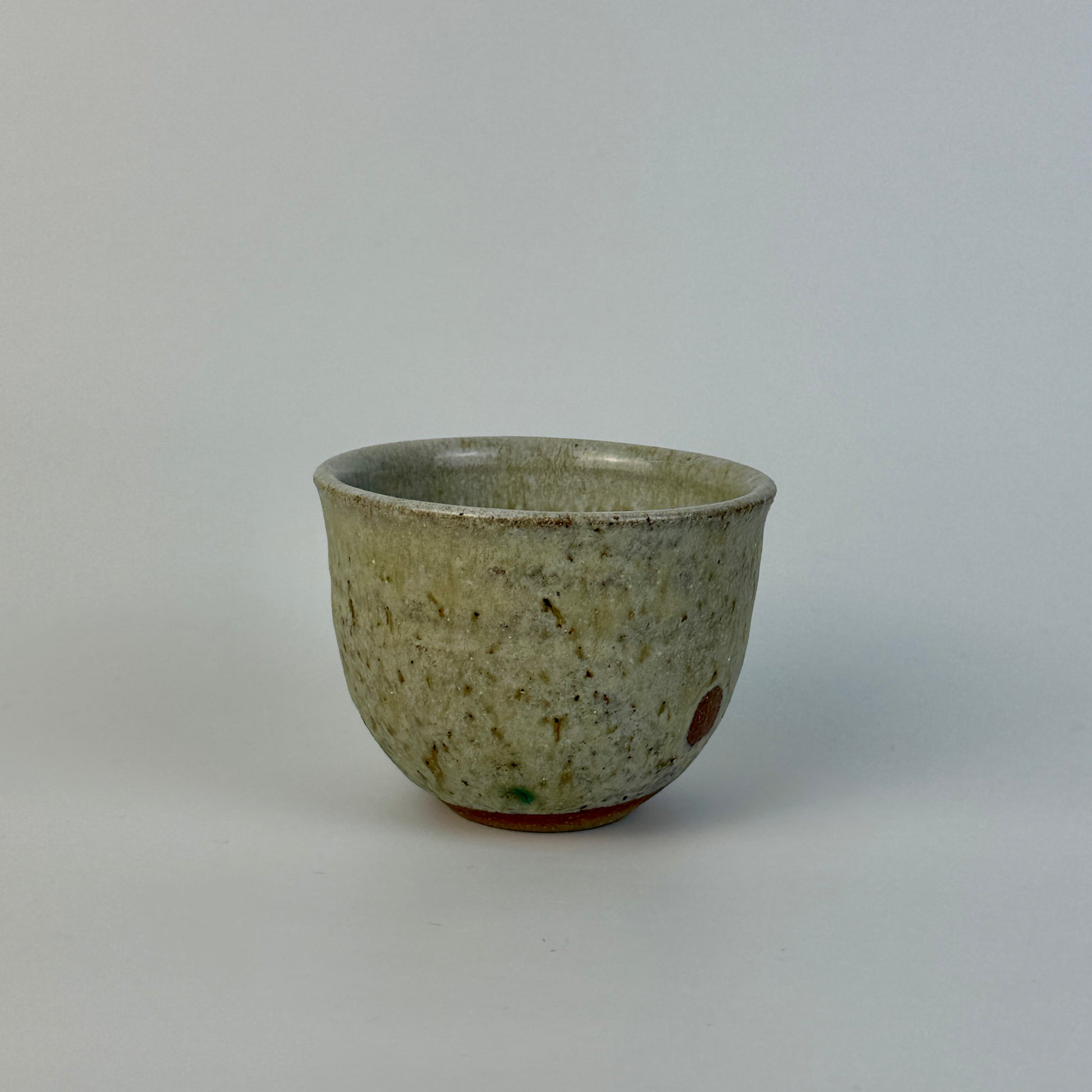 Ceramic cup with speckled glaze on a plain background